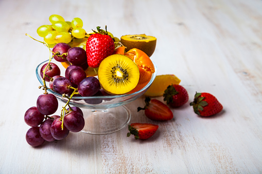 Ripe fruits on a transparent plate on a wooden background. Healthy eating.