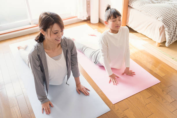 istock Mother and daughter stretching at home 902137044