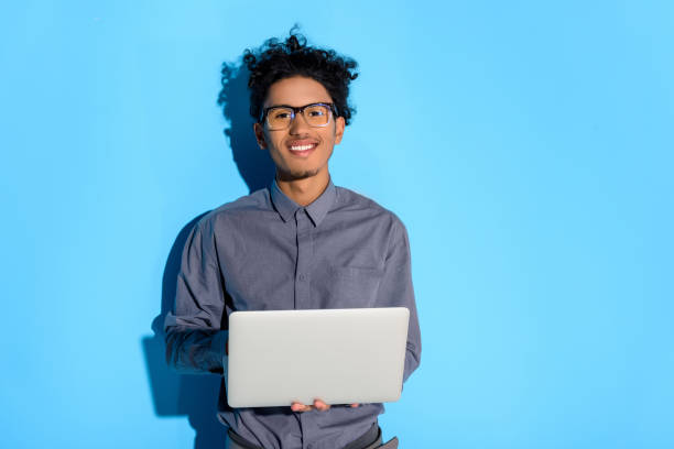 istock man holding laptop on blue background 902145750