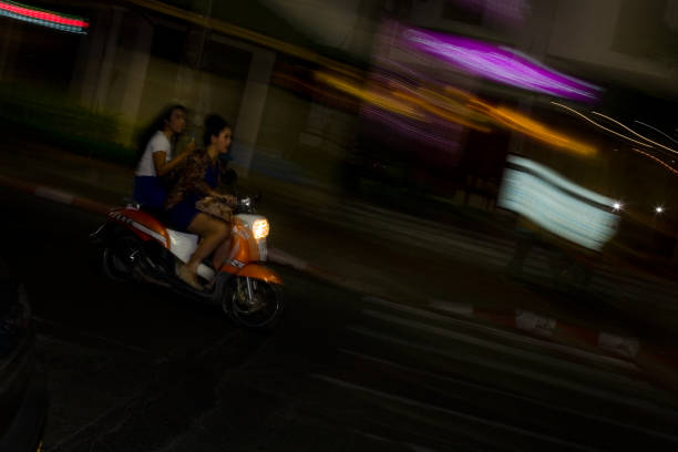 dwie dziewczyny szybko jeździć na rowerze przez nocne miasto. - crossing east driving transportation zdjęcia i obrazy z banku zdjęć