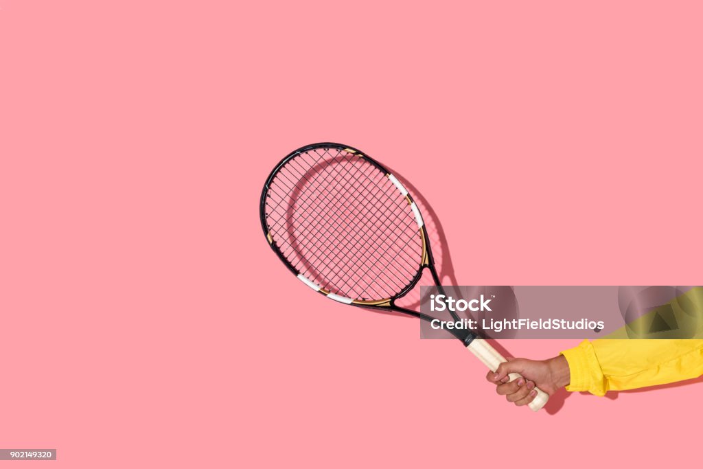 male hand holding tennis racket on pink background Close-up view of male hand holding tennis racket on pink background Human Hand Stock Photo