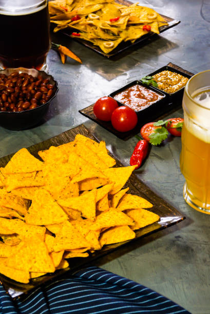 istock Nachos  with Tortilla chips tomato salsa, bean and mustard and two glass with beer on rustic stone background. A texture background.Copy paste place 902152746