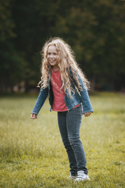 istock Pretty blonde smiling child wearing jeans jacket in park 902157016