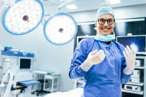 Happy woman surgeon ready for operation Portrait of happy woman surgeon standing in operating room, ready to work on a patient. Female medical worker in surgical uniform in operation theater. surgeon stock pictures, royalty-free photos & images