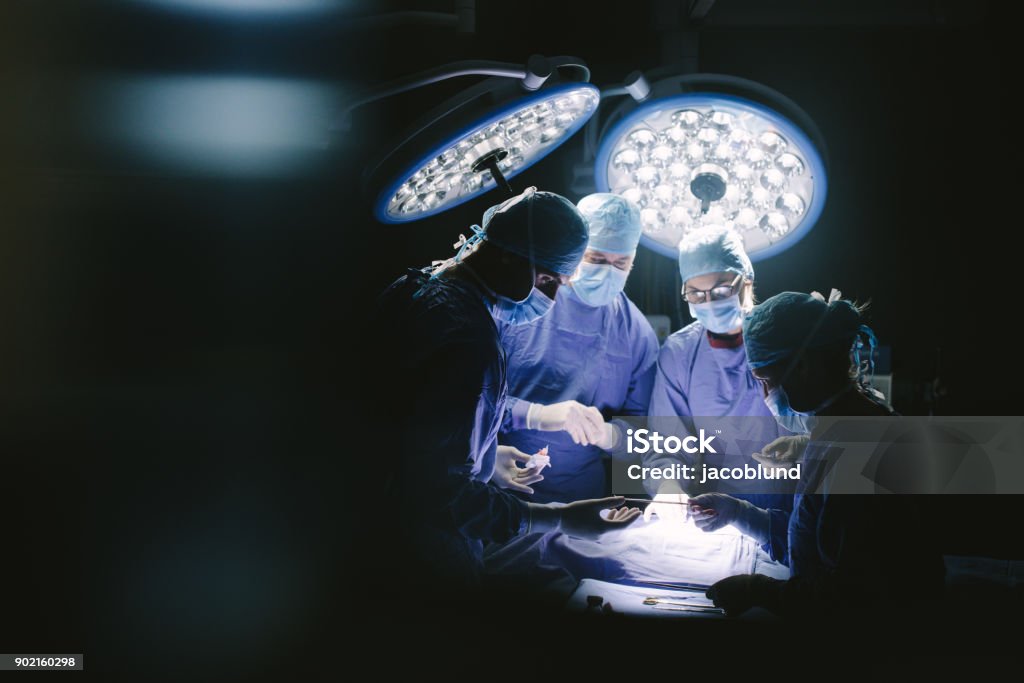 Team of professional surgeons performing surgery Team of professional surgeons performing surgery in hospital. Group of surgeons performing surgical procedure on patient in operation room. Surgery Stock Photo