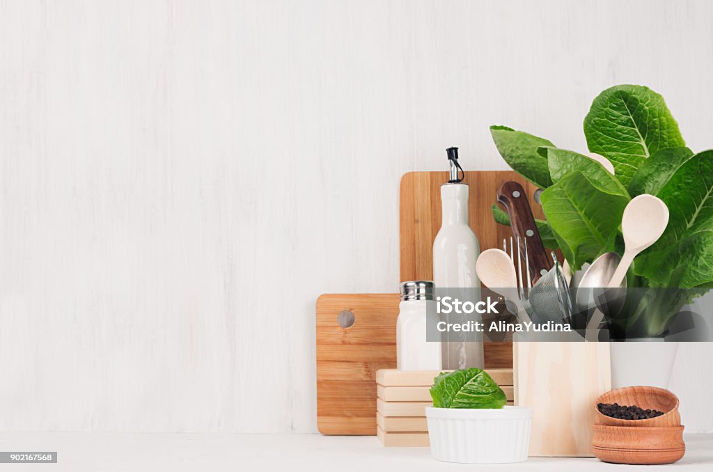Natural beige and brown wooden kitchenware and green plant on light white wood background, copy space. Cutting Board Stock Photo
