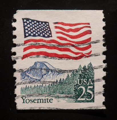 Image of USA flag and Yosemite National Park Stamp with black background.