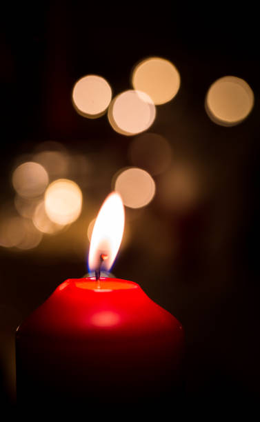 istock Burning red candle with golden colored bokeh and black background 902176198