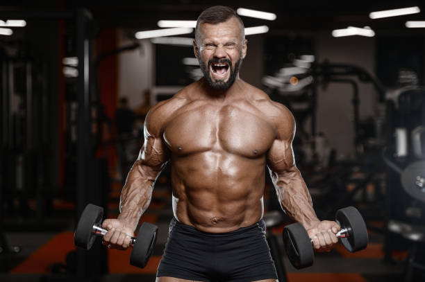 istock Old brutal strong bodybuilder athletic men pumping up muscles with dumbbells 902176320