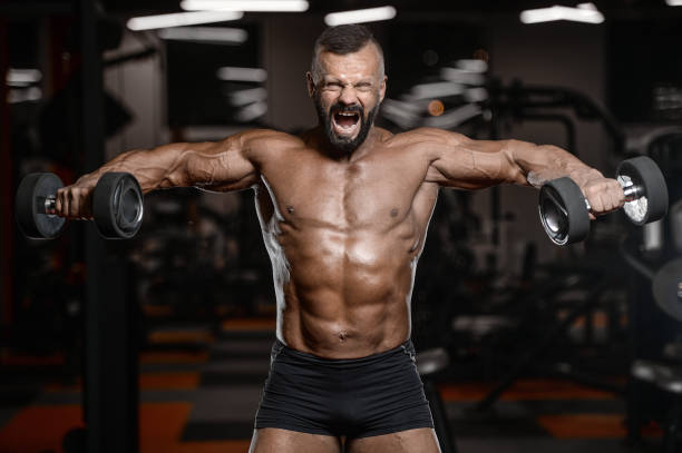 istock Old brutal strong bodybuilder athletic men pumping up muscles with dumbbells 902176806