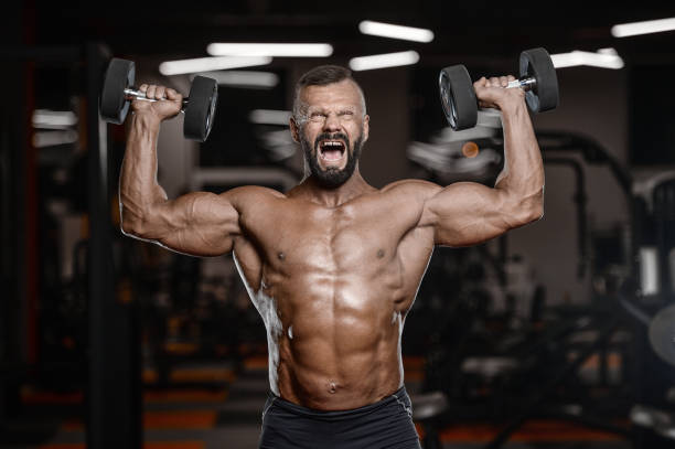 istock Old brutal strong bodybuilder athletic men pumping up muscles with dumbbells 902179912