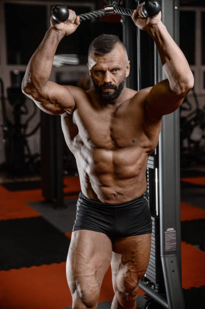istock Old brutal strong bodybuilder athletic men pumping up muscles with dumbbells 902180210