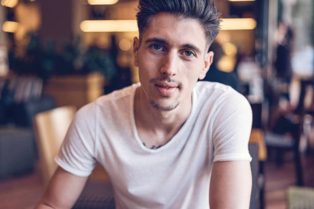 istock Attractive young man sitting indoors and looking at camera 902181948