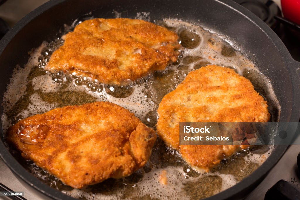 Frying wiener schnitzel in a hot pan Frying wiener schnitzel in a hot pan with cooking oil Fried Stock Photo