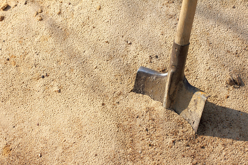 Old shovel with wooden handle stuck in the sand