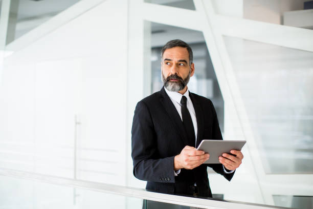 istock Handsome middle age businessman with digital tablet in the modren office 902184964