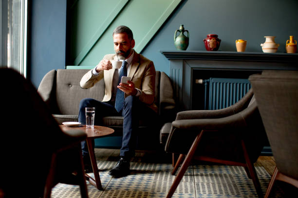 istock Handsome bearded businessman drinks coffee and making phone call 902187216