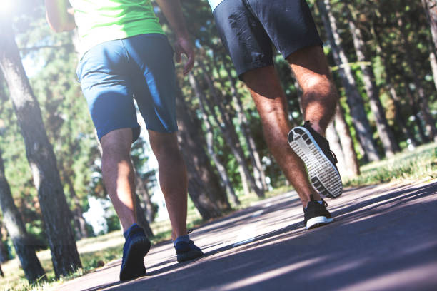 istock Two young men running in the park. 902187588