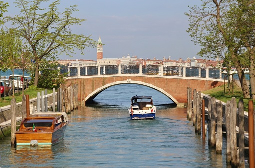 Bridge and canal on the island Lido di Venezia. In the background the Campanile of Venice. Italy, Europe.