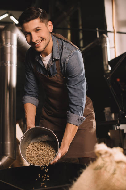istock coffee roaster pouring coffee beans into roasting machine 902192826