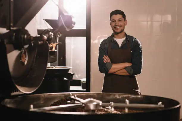 Photo of coffee roaster standing at roasting machine