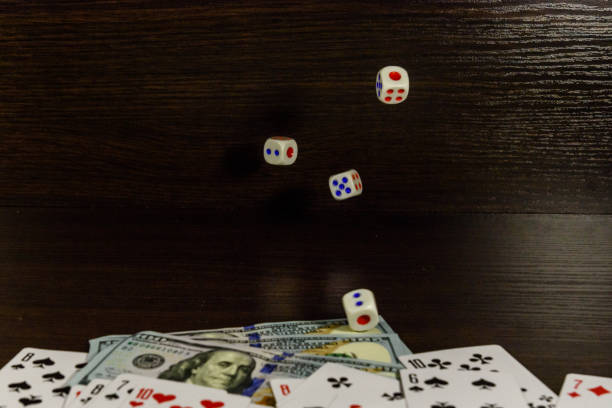 istock Dice in a flight above the one hundred dollar bills and playing cards. Gamble concept 902214620