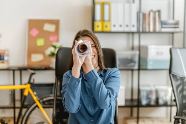 Woman searching trough hand made binocular Woman in the office searching binoculars stock pictures, royalty-free photos & images