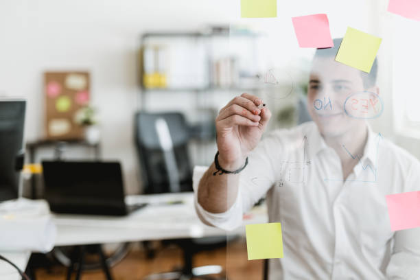 istock Young businessman writing on a glass wipe board 902217628