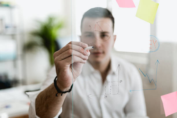 istock Young businessman writing on a glass wipe board 902217646