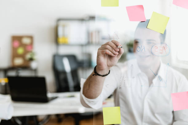 istock Young businessman writing on a glass wipe board 902217712