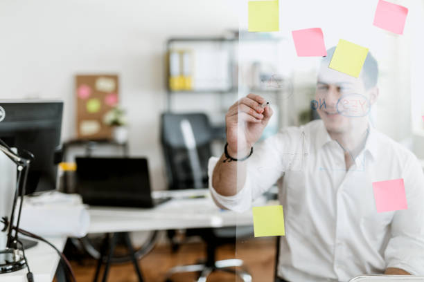 istock Young businessman writing on a glass wipe board 902217714