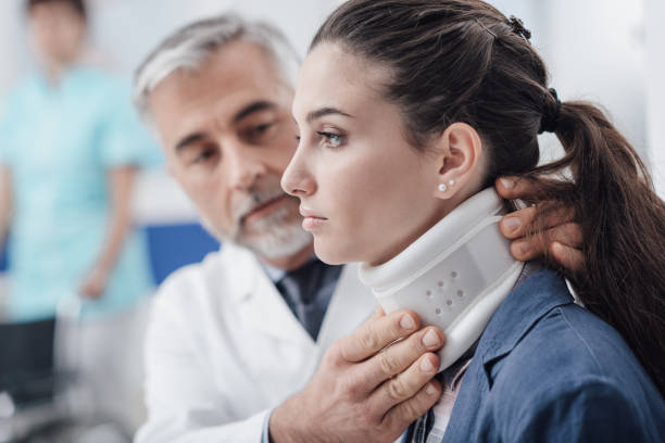 Doctor visiting a patient with cervical collar Professional doctor visiting a young injured patient at the hospital, he is adjusting her cervical collar neck stock pictures, royalty-free photos & images