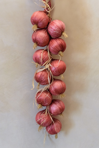 braided red onions hanging on the wall