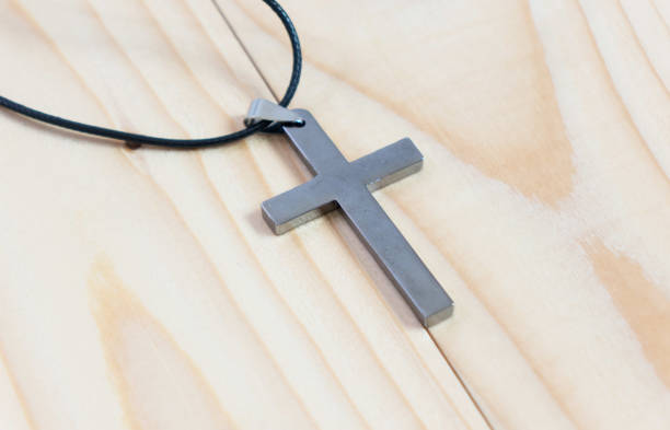 istock Necklace with silver cross on wooden table 902225270