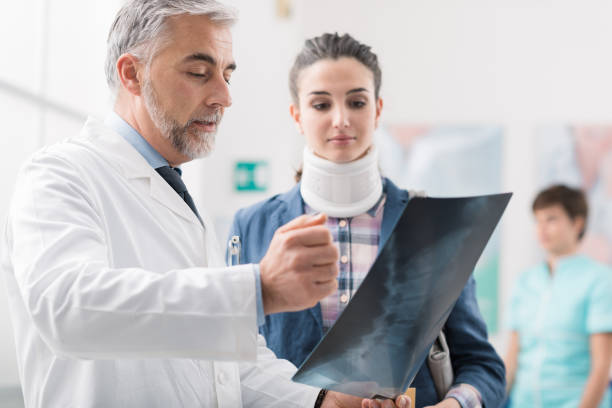 Doctor examining a young female patient's x-ray Doctor examining a young female patient's x-ray, she is wearing a cervical collar and having a serious neck injury human spine photos stock pictures, royalty-free photos & images
