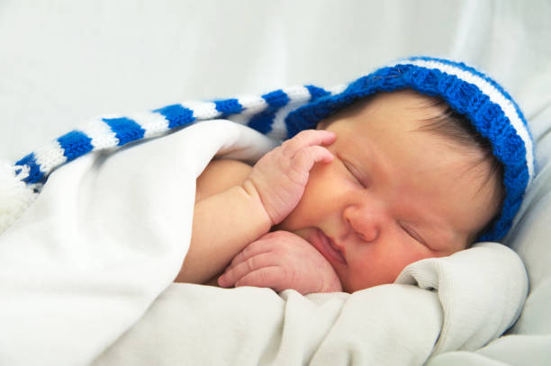 visage de bébé heureux au chapeau, nouveau-né présentant un ictère sur couverture blanche, soins de santé infantile - yellowing photos et images de collection