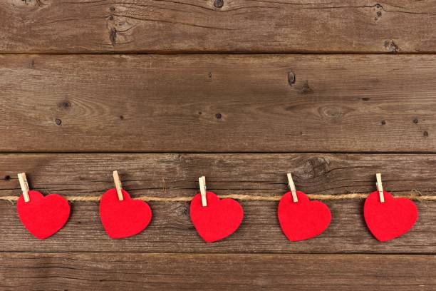 istock Cloth hearts on a line, bottom border against rustic wood 902268750