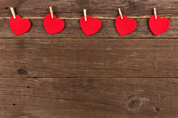 istock Cloth hearts on a line, top border against rustic wood 902268768