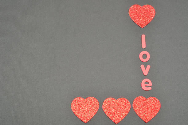 istock The word love on a black background decorated with five red glitter hearts 902272468