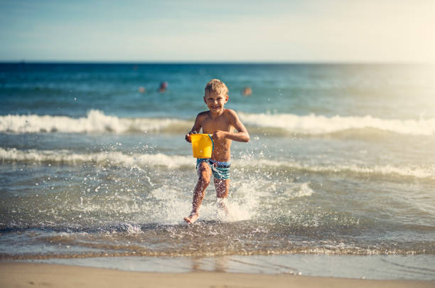 Red headed boy playing on a sandy beach in UK