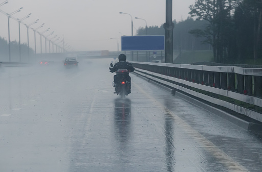 motorcyclist moves on motorcycle on highway to rainy weather