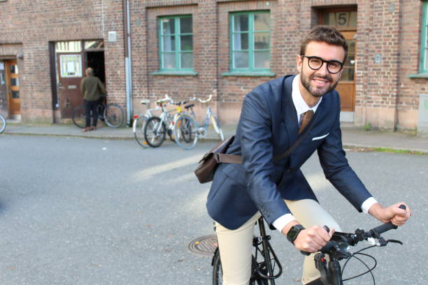 hombre de negocios guapo rumbo al trabajo en bicicleta - business looking at camera office new fotografías e imágenes de stock