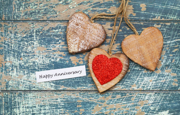 Happy Anniversary card with three wooden hearts on rustic wooden surface Happy Anniversary card with three wooden hearts on rustic wooden surface anniversary card stock pictures, royalty-free photos & images