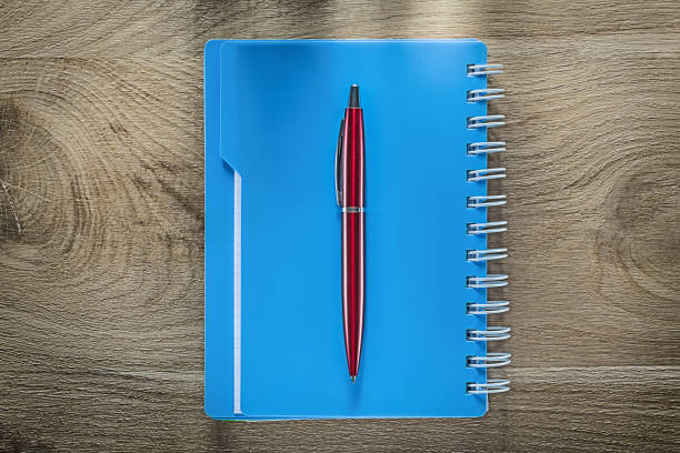 istock Biro pen spiral copybook on wooden board 902331760