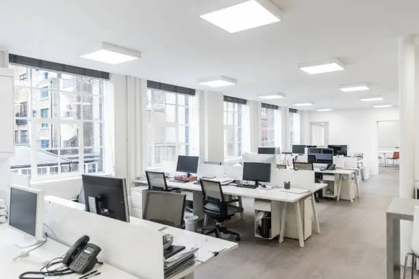 Photo of Large contemporary office environment with empty stations and electric ceiling lights