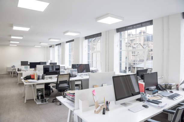 istock Contemporary office space with computer monitors on desks and large windows 902338300