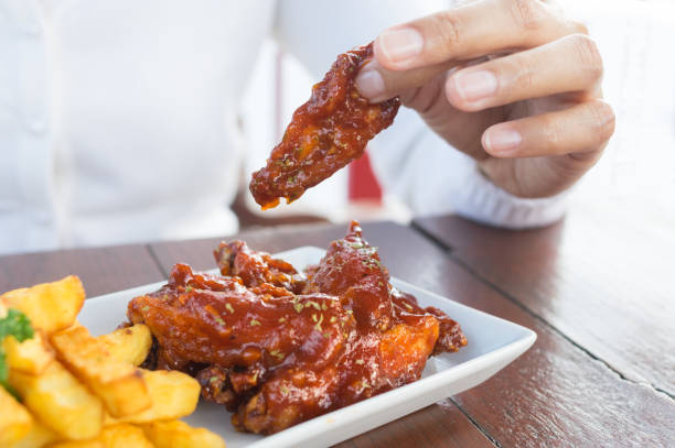 istock Woman eating chicken wing and potato chips. 902338616