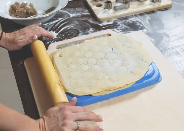 istock Female hands roll out the dough on a dumpling mold at home 902384188