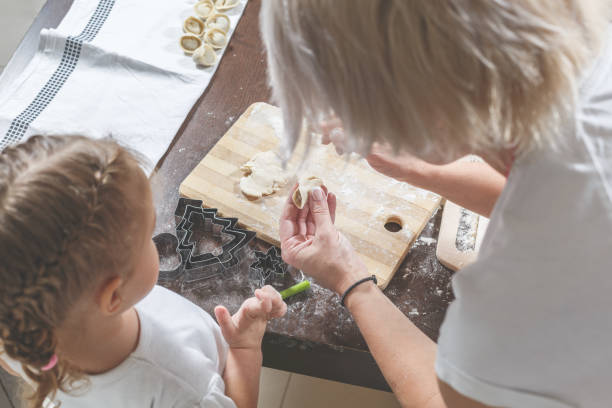 istock Mom shows little daughter how to make dumplings 902384234