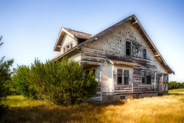 Beautiful crumbling two story farm house A large beautiful wooden two story abandoned farm house with peeling paint and broken windows in a rural summer countryside run down stock pictures, royalty-free photos & images